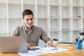 Young businessman sitting and checking financial documents displayed in chart format.