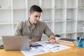 Young businessman sitting and checking financial documents displayed in chart format.