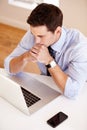 Doing his planning. Young businessman sitting with his arms crossed in front of his laptop.