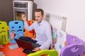 Young businessman sitting inside baby playground using laptop at home