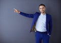 Young businessman sitting isolated on grey background.