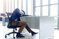 A young businessman sitting in a modern office. He has a feel sleepy because hard work so tired weary fatigued and exhausted. On