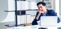 A young businessman sitting in a modern office. He has a feel sleepy because  hard work so tired weary fatigued and exhausted. On Royalty Free Stock Photo