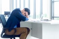 A young businessman sitting in a modern office. He has a feel sleepy because hard work so tired weary fatigued and exhausted. On