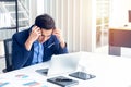 A young businessman sitting in a modern office. He has a feel stressed about the result of business profits not positive. On his Royalty Free Stock Photo