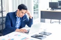 A young businessman sitting in a modern office. He has a feel stressed about the result of business profits not positive. On his Royalty Free Stock Photo