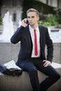 Young businessman sitting on platform while using cell phone