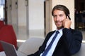 Young businessman sitting relaxed on sofa at hotel lobby making a phone call, waiting for someone. Royalty Free Stock Photo