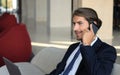 Young businessman sitting relaxed on sofa at hotel lobby making a phone call, waiting for someone. Royalty Free Stock Photo