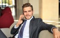 Young businessman sitting relaxed on sofa at hotel lobby making a phone call, waiting for someone. Royalty Free Stock Photo