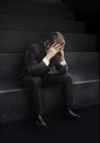 Young businessman sitting on stairs with head down Royalty Free Stock Photo