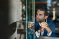 Young businessman sitting by a window inside of a cafe Royalty Free Stock Photo