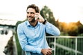 A young businessman with smartphone standing on a bridge at sunset, making a phone call. Royalty Free Stock Photo