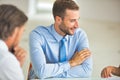 Young businessman smiling while colleagues discussing at table during meeting in office Royalty Free Stock Photo