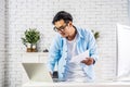 Young businessman smiling happy asian man working holding a piece of paperwork and reading while standing in front of laptop at Royalty Free Stock Photo