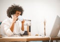 Young businessman speaks on mobile phone while working with a computer. Arab guy drinks coffee while sitting at a desk Royalty Free Stock Photo