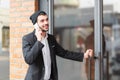 Young businessman speaks on the phone and opens the door of the building Royalty Free Stock Photo