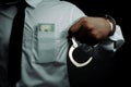 Young businessman standing holding money and handcuffs attached to his arm Concept Corrupt police, bad cop, bribe police