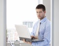 Young businessman standing with laptop in hand