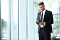 Young businessman standing in an office near the window and talking on a cell phone. Royalty Free Stock Photo