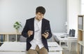 Young businessman standing in office and using online banking app on mobile phone Royalty Free Stock Photo