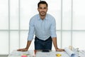 Young businessman standing in office beside working desk and engineer tools and equipment Royalty Free Stock Photo