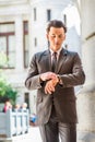 A young businessman is standing outside an office building, looking down and checking time Royalty Free Stock Photo