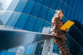 A young businessman stands on a blue background in a business suit holding documents. The concept of meeting businessmen