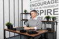 a young businessman in a strict gray suit enjoys listening to music on headphones against the background of an office Royalty Free Stock Photo