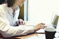 Young businessman or student, long hair, working writing on keyboard near window with open laptop Royalty Free Stock Photo