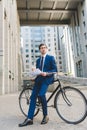 young businessman in stylish suit with newspaper and paper cup of coffee leaning Royalty Free Stock Photo