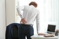 Young businessman suffering from back pain in office