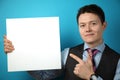 Young businessman in suit on blue background holding banner in his hands, poster placard with empty space for text Royalty Free Stock Photo