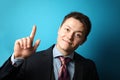 Young businessman in suit on blue background shows his hand thumbs up, symbol of success Royalty Free Stock Photo