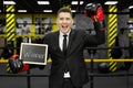 Young businessman in a suit in a boxing ring wearing gloves holds a sign with the inscription winner