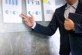 Young businessman in the suit explaining data charts on the wall in a office