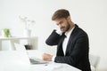 Young businessman in suit feeling neck pain after sedentary work