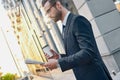 Young businessman in suit and glasses holding a paper cup and reading business newspaper in his hands Royalty Free Stock Photo