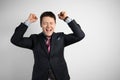 Young businessman in a suit on a gray background celebrating victory and success. Happy and excited expressing Royalty Free Stock Photo