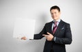 Young businessman in suit on gray background holding banner in his hands, poster placard with empty space for text Royalty Free Stock Photo