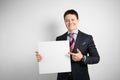 Young businessman in suit on gray background holding banner in his hands, poster placard with empty space for text Royalty Free Stock Photo