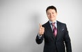 Young businessman in suit on gray background shows his hand thumbs up, symbol of success Royalty Free Stock Photo
