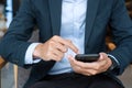 Young Businessman in suit holding and using smartphone for sms messages, man typing touchscreen mobile phone in office or cafe. Royalty Free Stock Photo