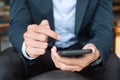 Young Businessman in suit holding and using smartphone for sms messages, man typing touchscreen mobile phone in office or cafe. Royalty Free Stock Photo