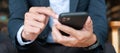 Young Businessman in suit holding and using smartphone for sms messages, man typing touchscreen mobile phone in office or cafe. Royalty Free Stock Photo