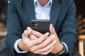 Young Businessman in suit holding and using smartphone for sms messages, man typing touchscreen mobile phone in office or cafe. Royalty Free Stock Photo