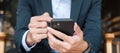 Young Businessman in suit holding and using smartphone for sms messages, man typing touchscreen mobile phone in office or cafe. Royalty Free Stock Photo