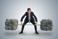 Young businessman in suit is lifting heavy weights. Royalty Free Stock Photo