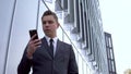 A young businessman in a suit speaks on the phone. Serious man stands in front of a mirror business center Royalty Free Stock Photo