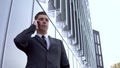 A young businessman in a suit speaks on the phone. Serious man stands in front of a mirror business center Royalty Free Stock Photo